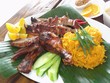 Chamorro beef and chicken barbeque meal with yellow rice in banana leaves Authentic Chamorro favorite cuisine of beef and chicken barbeque served with yellow rice, cucumber and lemon slices. Chamorro beef and chicken barbeque meal with yellow rice in banana leaves Authentic Chamorro favorite cuisine of beef and chicken barbeque served with yellow rice, cucumber and lemon slices.