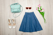 Jeans skirt, glasses, white shoes, handbag and a bouquet of tulips. Fashionable concept. Wooden background. Jeans skirt, glasses, white shoes, handbag and a bouquet of tulips. Fashionable concept. Wooden background.