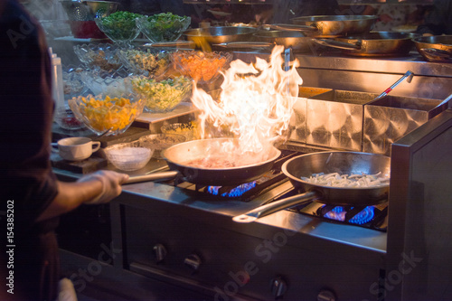 Fotoobraz na płótnie Szef kuchni w kuchni restauracji w piecu z patelni, robi flambe na jedzenie. niska selektywność skupienia ligth.