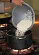 Cooking rice in a pot white rice poured out into a boiling kettle from a basin Cooking rice in a pot white rice poured out into a boiling kettle from a basin