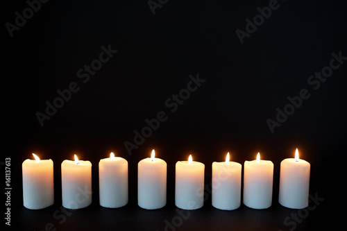 candles burning in darkness over black background