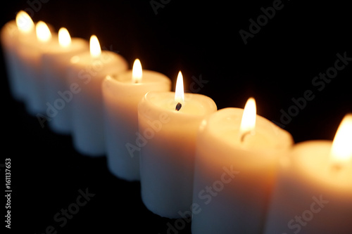 candles burning in darkness over black background