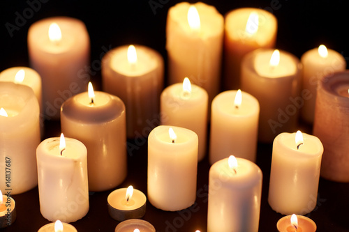 candles burning in darkness over black background