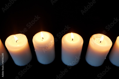 candles burning in darkness over black background