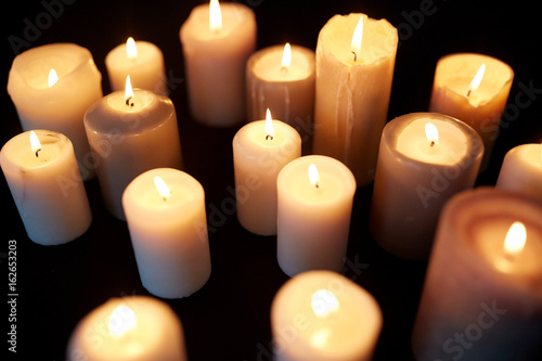 candles burning in darkness over black background