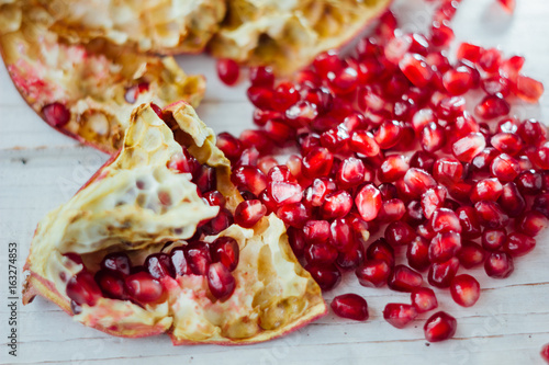 Pomegranate peel and seeds over white wooden background.