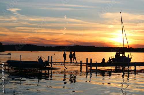 Zdjęcie XXL Letni zachód słońca nad jeziorem. Krajobraz z złotym zmierzchem i sylwetkami ludzie cieszy się pięknego wieczór na jeziornym Mendota molu w mieście Madison, Wisconsin, usa.