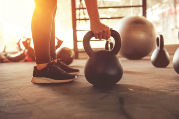 Fitness training with kettlebell in sport gym with sunlight effect.