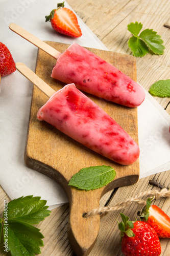Plakat Świeży domowej roboty truskawkowy lody na drewnianym tle. Popsicles organiczne i wegańskie