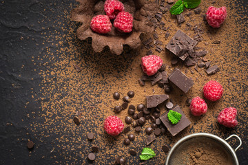 Pieces of chocolate, fresh raspberries and tartlets. Preparation. Food dessert background.
