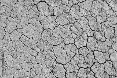 Fototapeta Cracked dry earth texture background. Clay desert surface. Discolored illustration for global warming news.