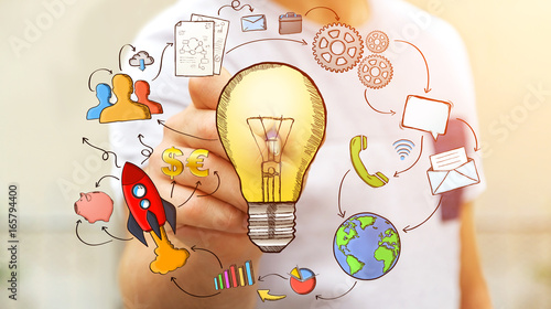 Businessman drawing a lightbulb with a pen with multimedia icons