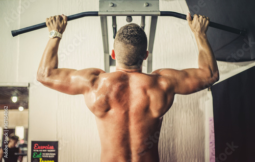 Plakat Atrakcyjny młody mięśniowy mężczyzna pracujący out jego plecy przy gym