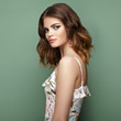 Brunette young woman in floral spring summer dress. Girl posing on a green background. Summer floral outfit. Stylish wavy hairstyle. Fashion photo. Brunette lady Brunette young woman in floral spring summer dress. Girl posing on a green background. Summer floral outfit. Stylish wavy hairstyle. Fashion photo. Brunette lady
