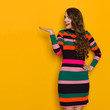 Surprised Young Woman In Colorful Striped Dress Is Presenting Surprised Young Woman In Colorful Striped Dress Is Presenting