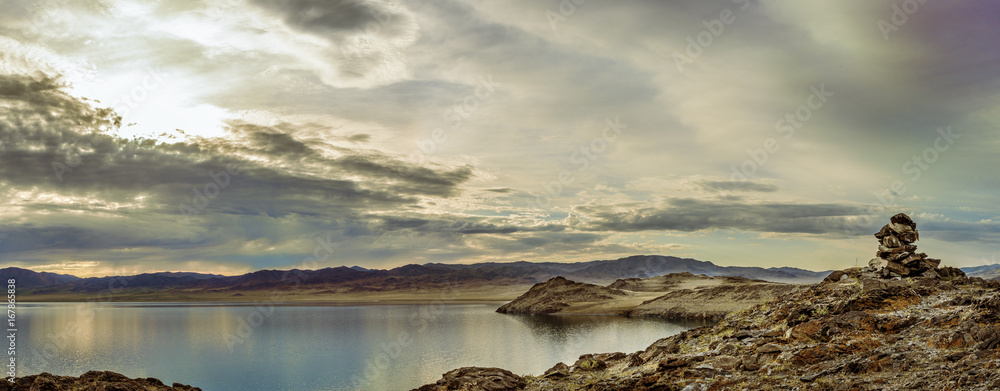 picturesque view of lake surrounded by mountains with cloudy sky on background 
