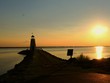 A lighthouse silhouetted by a beautiful sunset, with silhouettes of people around A lighthouse silhouetted by a beautiful sunset, with silhouettes of people around
