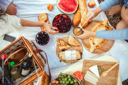 Zdjęcie XXL Zestaw piknikowy z owocami, serem, grzanką, miodem, winem z wiklinowym koszem i kocem. Piękny lata tło z dziewczyną i produktami na naturze