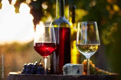 Two glasses of white and red wine with food at sunset