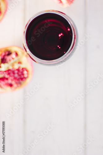 Organic pomegranate wine on white wooden table.