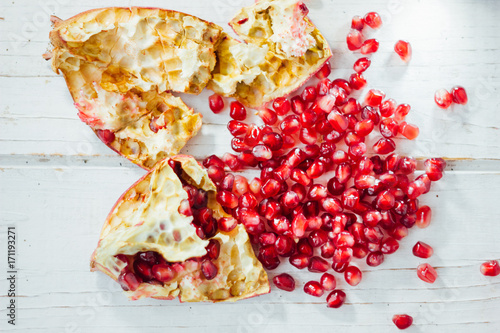Pomegranate peel and seeds over white wooden background.