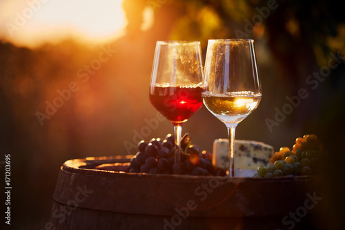 Two glasses of white and red wine with food at sunset
