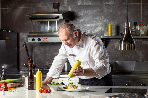 Plakat Szef kuchni w kuchni hotelowej lub restauracyjnej, pracuje nad sosem na jedzenie jako saucier