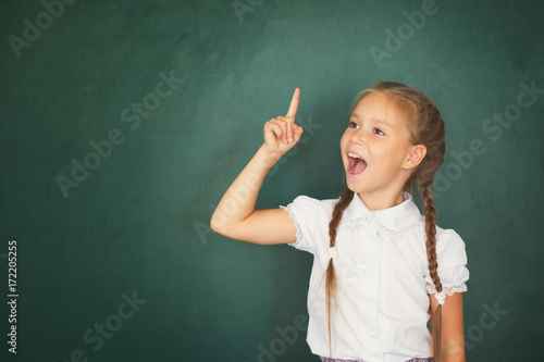Plakat Uśmiechnięta młoda małe dziecko dziewczyna w szkole na blackboard tle. Koncepcja edukacji i szkoły