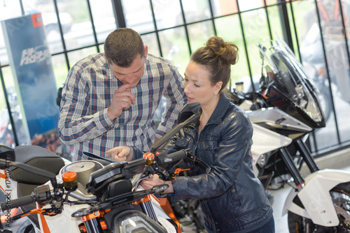 Zdjęcie XXL kobieta sprzedaje motocykl do dojrzałego mężczyzny w sklepie motocyklowym