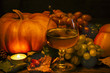a glass of grape juice, pumpkins, grapes, apples. on a wooden surface. against a dark background a glass of grape juice, pumpkins, grapes, apples. on a wooden surface. against a dark background