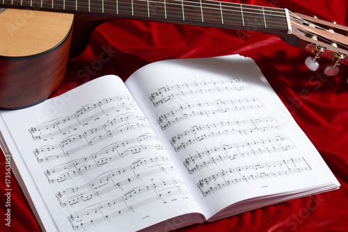 Plakat gitara akustyczna i nuty na czerwonym aksamicie tkaniny, Zamknij widok obiektów