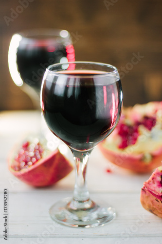 Organic pomegranate wine on white wooden table.