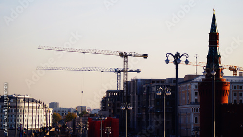 Plakat Żurawie wieżowe, dźwigi budowlane w mieście Moskwa, część Kremla i słynny most