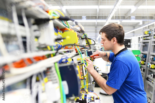 Fotoobraz na płótnie Montaż elektroniki w mechanice - pracownicy w fabryce Hi Tech // Montaż elektroniki w inżynierii mechanicznej - pracownicy w fabryce Hi-Tech