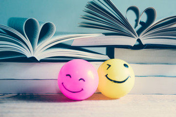 Self made hand drawn smiley face ball in yellow and pink surrounded by a lot of books - Retro Vintage filte