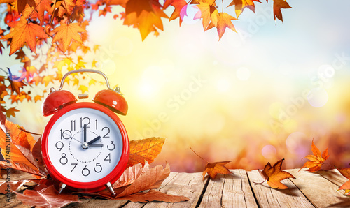 Daylight Savings Time Concept - Clock And Leaves On Wooden Table
