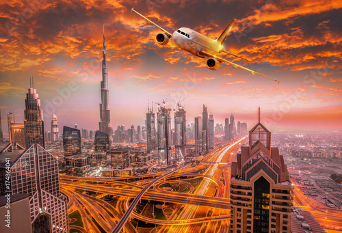 Plakat Samolot lata nad Dubaj przeciw kolorowemu zmierzchowi w Zjednoczone Emiraty Arabskie