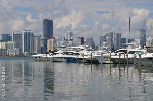 Plakat Szeroki wybór łodzi rekreacyjnych zacumowany przy marinie Key Biscayne z condo Miami i panoramą handlową budynku w tle.