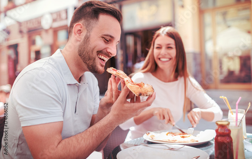 Plakat Piękna młoda para siedzi w kawiarni i jedzenie pizzy. Konsumpcjonizm, jedzenie, koncepcja stylu życia