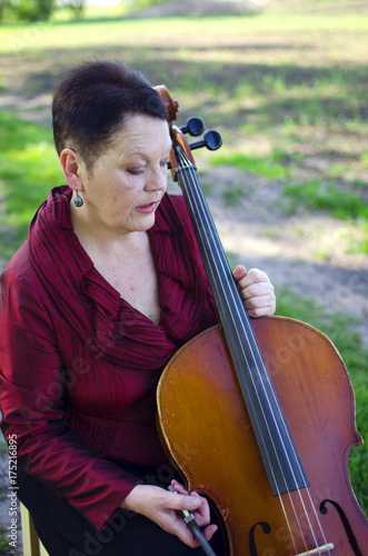 Plakat Dorosła muzyk kobieta bawić się na violoncello outdoors. Nauczyciel muzyki gra na wiolonczeli