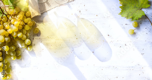 grapes on white table; seasoning vineyard background; Bottle and glasses