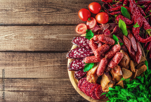 Plakat Tacka na jedzenie z pysznym salami, kawałki plasterki szynki, kiełbasa, pomidory, sałatka i warzywo.