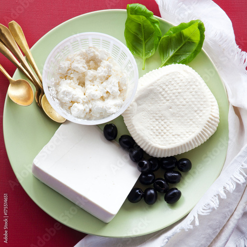 Plakat grupa białych serów: ricotta, sycylijska primosale i owczy ser na talerzu. przekąski z oliwkami