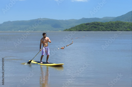 Zdjęcie XXL Młody człowiek uprawiania paddleboarding, wstać wiosła, wiosłowania. Surfing z wiosłowaniem.