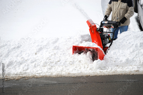 man operating snow blower to remove snow on driveway