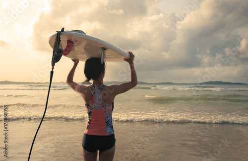 Plakat Tylni widok młoda kobieta surfingowiec z białym surfboard odprowadzeniem morze