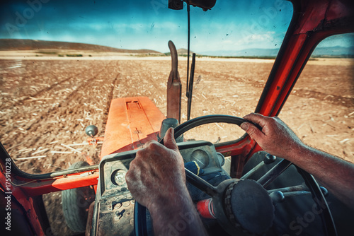 Closeup hands of farmer, sits inside in the tractor cabin