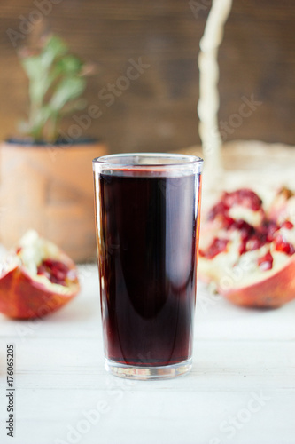 Pomegranate juice in glass surrounded by pomegranate halves.