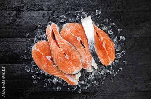 Salmon steaks on ice on black wooden table top view