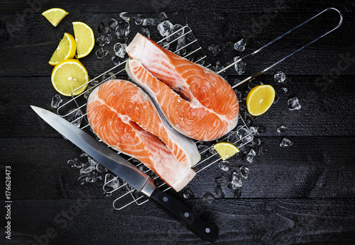 Salmon steaks on ice on black wooden table top view